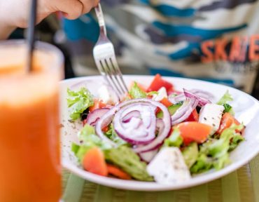 Colorful salad with fresh vegetables and a refreshing drink on a table.